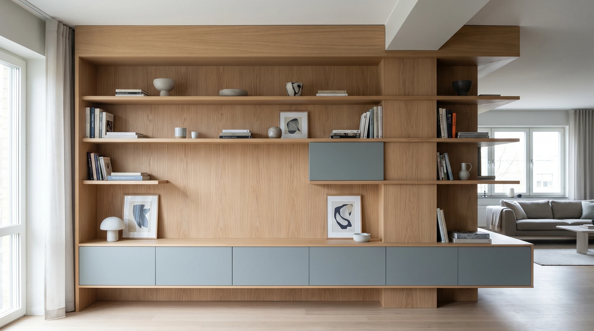 Modern bokhylla i ljust trä med grå skåp och dekorativa föremål